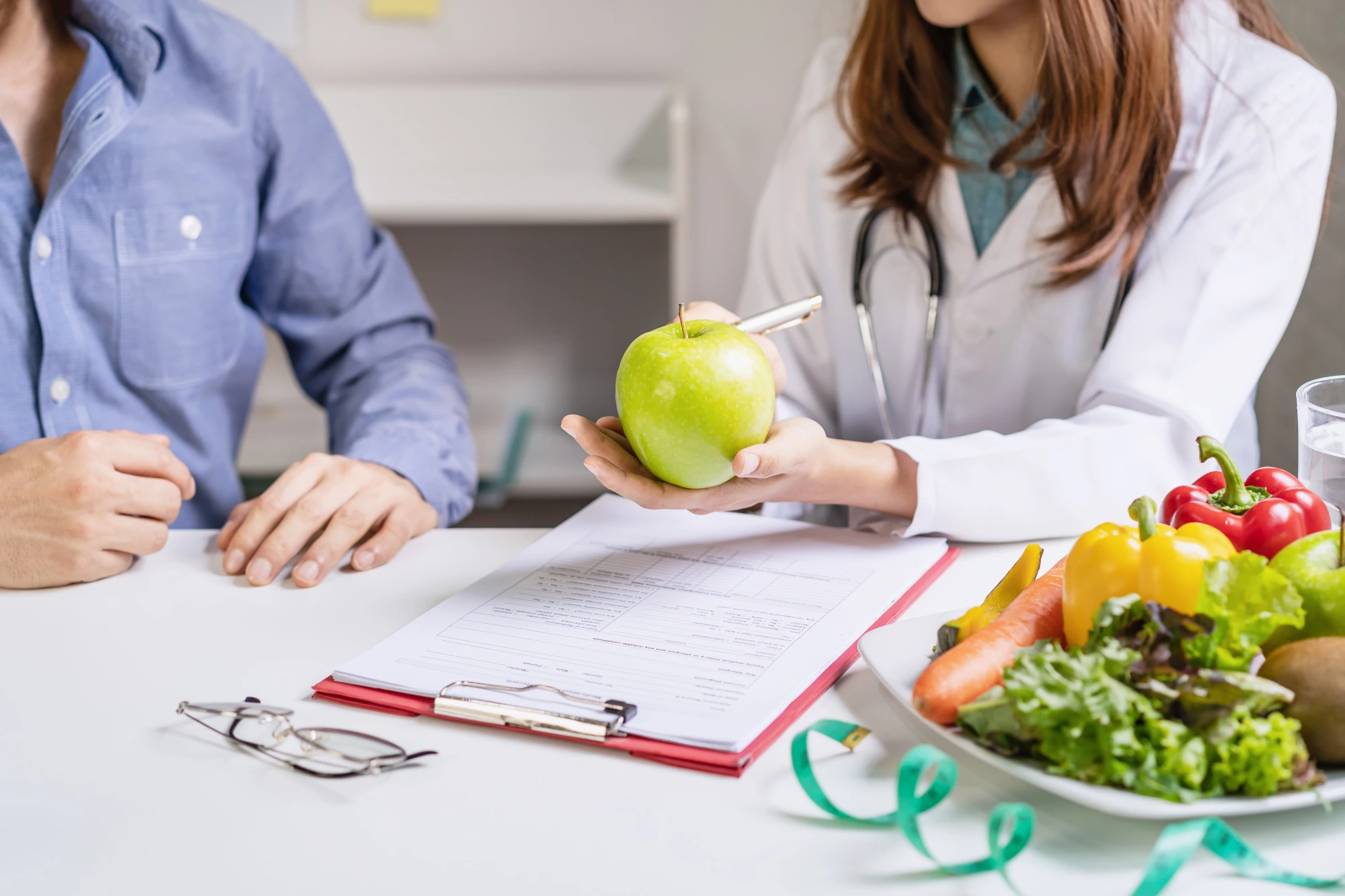 Doctor discussing nutrition with patient and apple.
