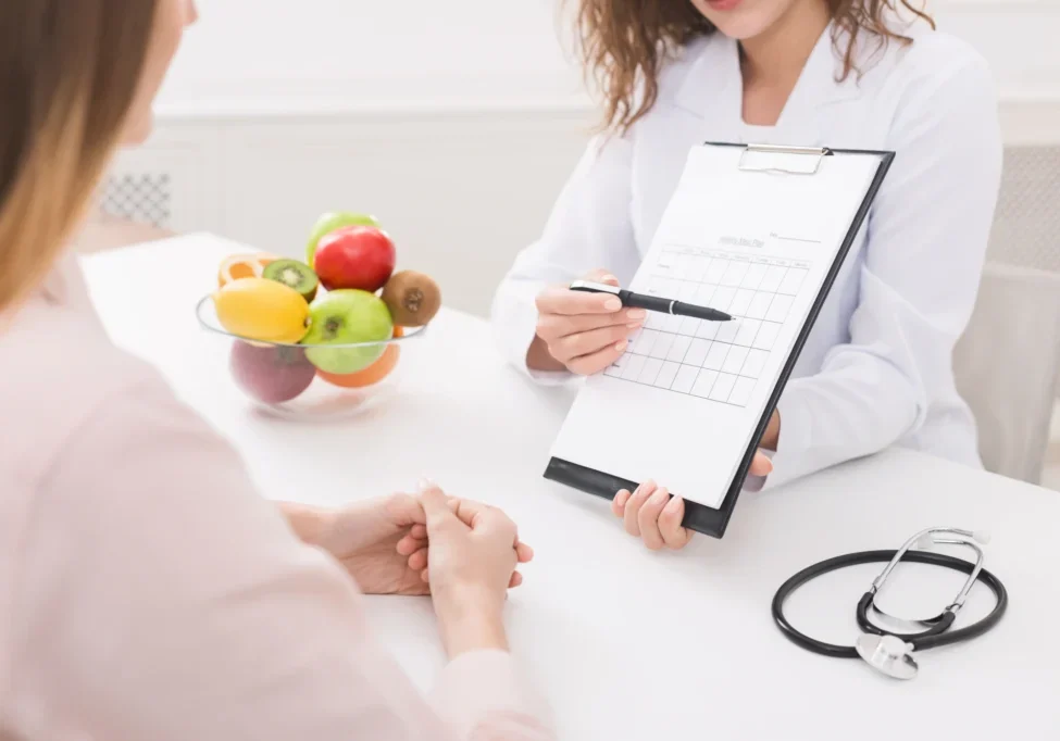 Nutrition consultation with clipboard and fruits.